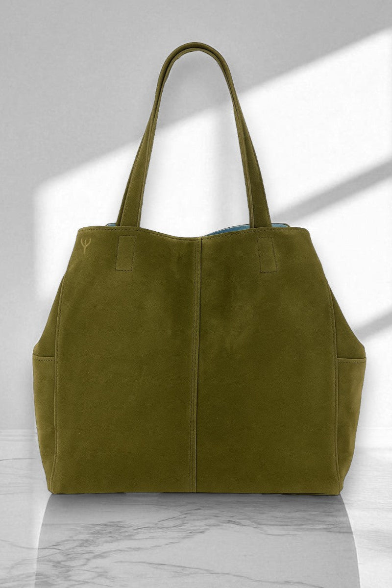 Green suede tote bag on a marble surface with a light gray background