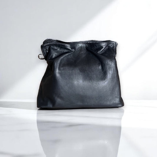 Soft leather clutch bag in Black Leather by Taylor Yates – front view on a white marble surface